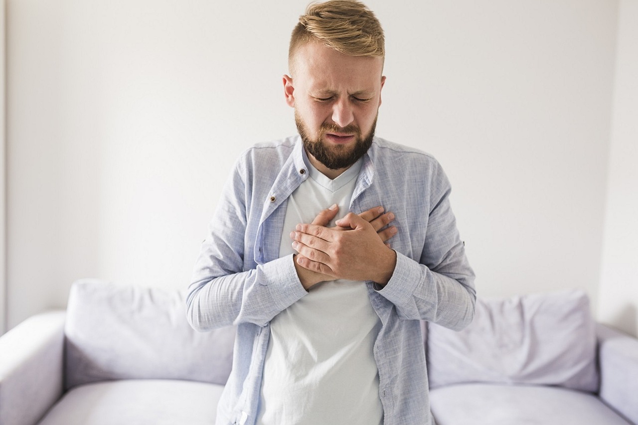 Man experiencing heartburn with two hands on his chest