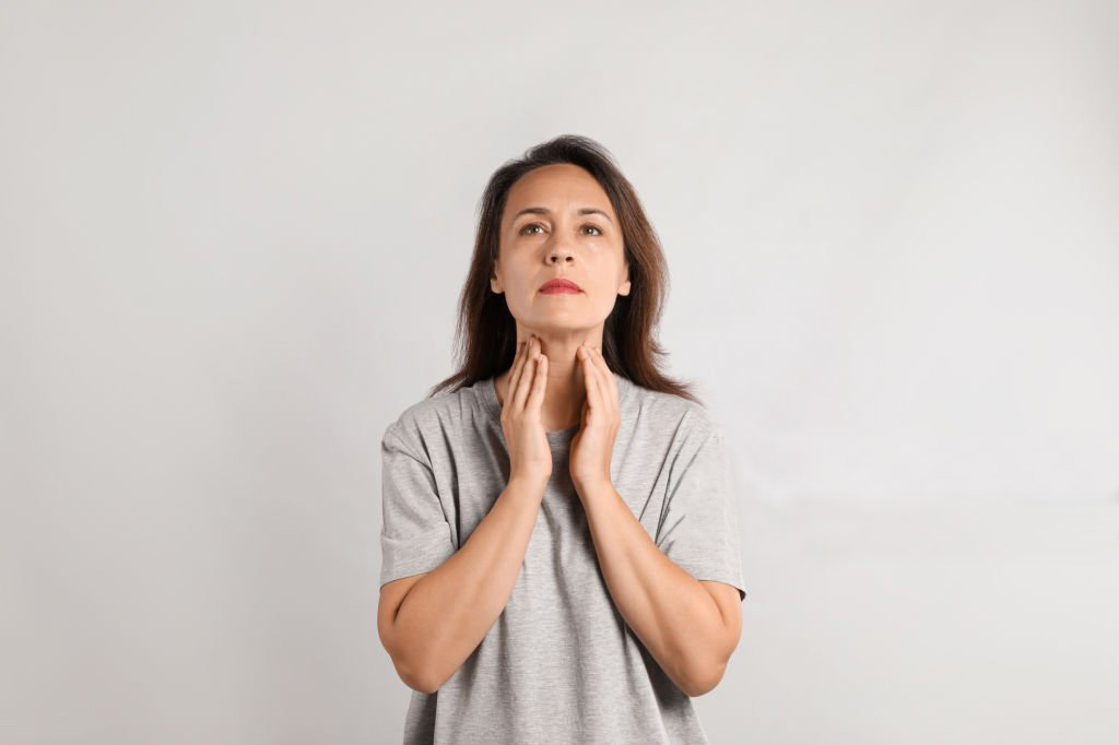 Woman with hypothyrodism holding neck