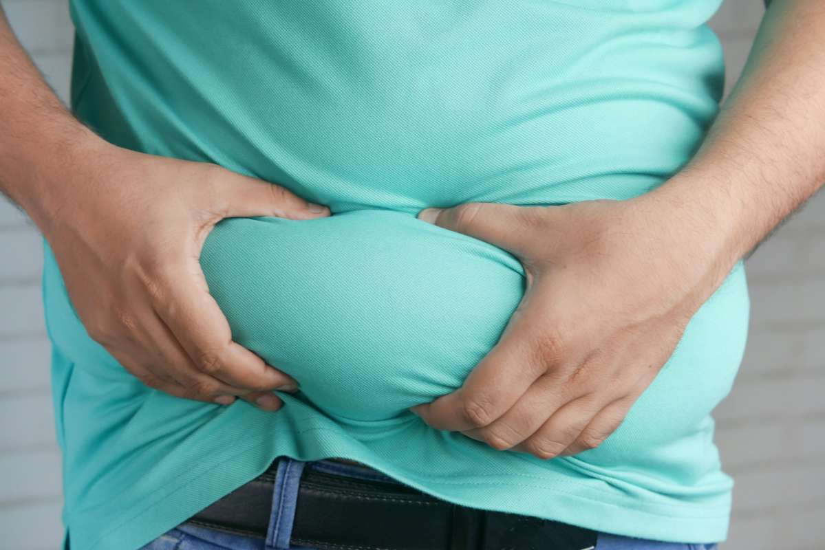 Person experiencing weight gain. Holding excess fat acculumated around the belly.